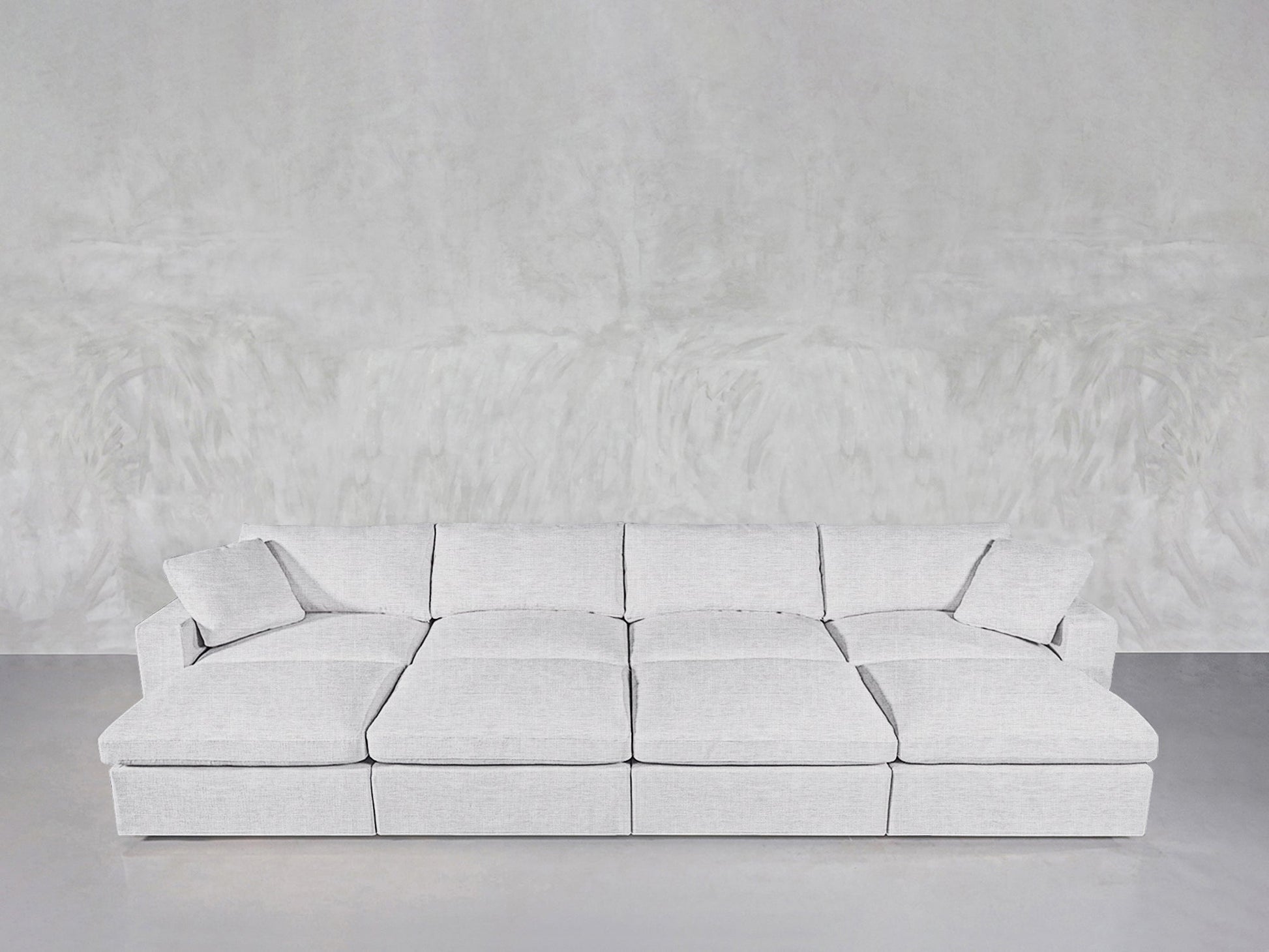 An 8-Seat Modular Daybed with a modern, minimalist design in light gray rests against a textured light gray wall on a smooth floor.