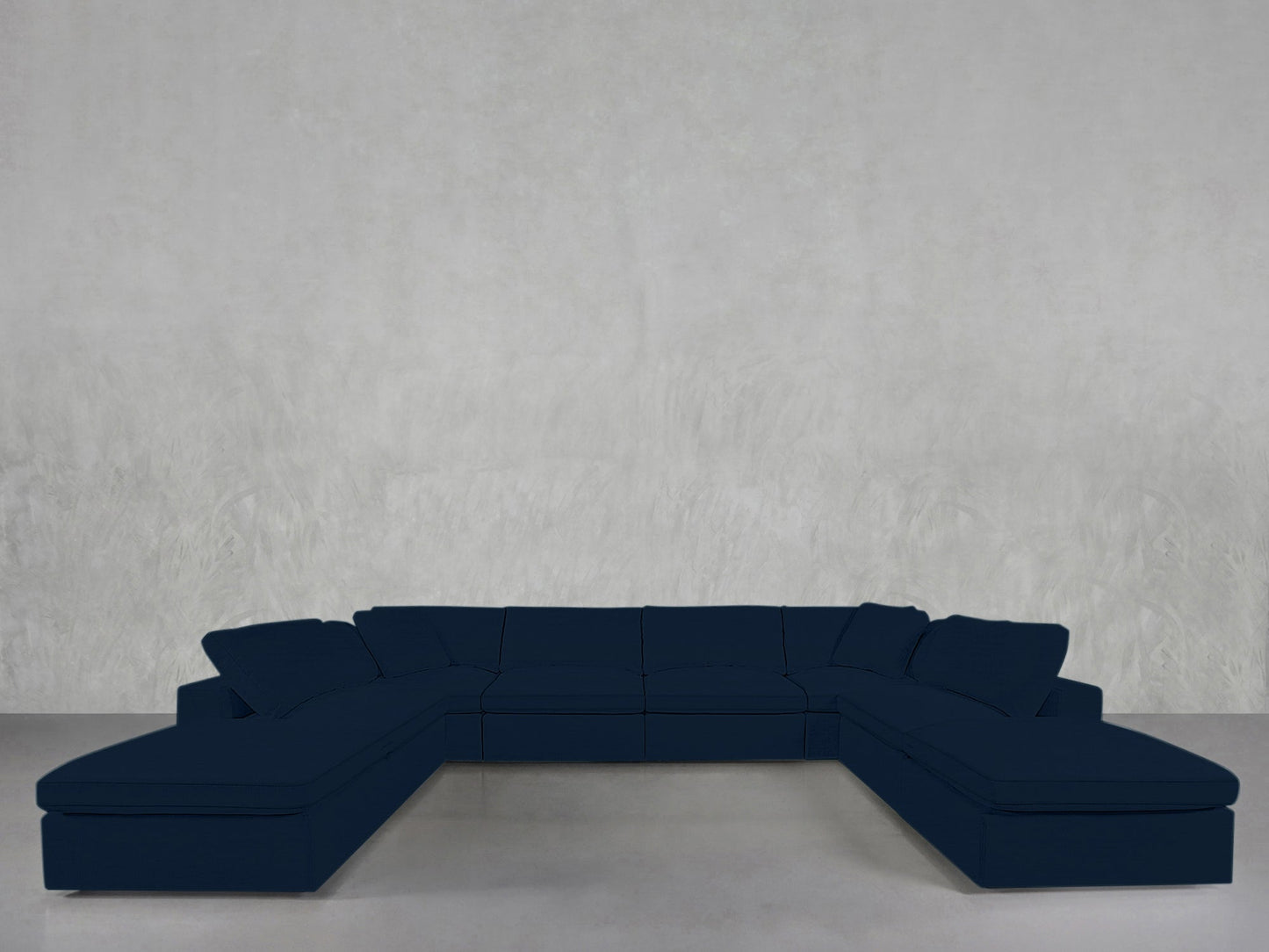 An 8-Seat Modular Double Lounger U-Sectional in dark blue with cushions is positioned against a plain light gray wall on a smooth floor.