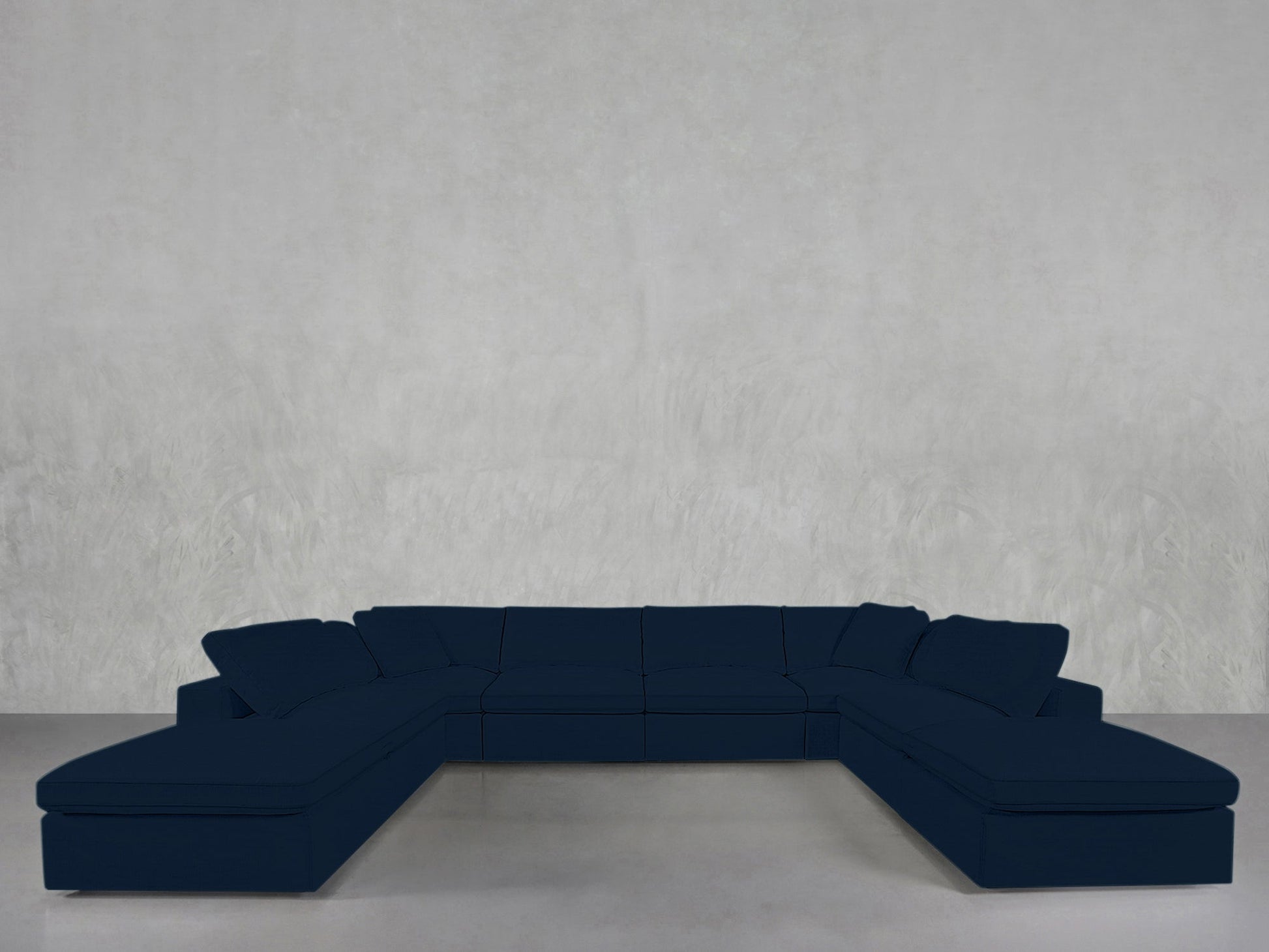 An 8-Seat Modular Double Lounger U-Sectional in dark blue with cushions is positioned against a plain light gray wall on a smooth floor.
