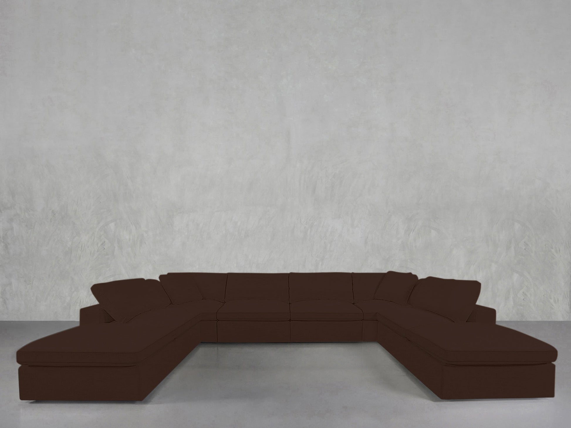 An 8-Seat Modular Double Lounger U-Sectional in dark brown is arranged against a plain, light gray textured wall atop a smooth, light gray floor.