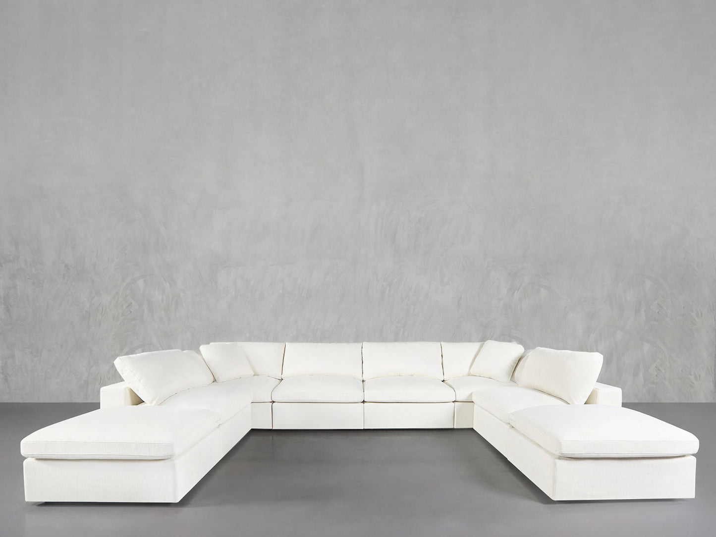 An 8-Seat Modular Double Lounger U-Sectional in modern white is arranged in a U-shape against plain light gray walls and flooring, showcasing clean lines and contemporary style.