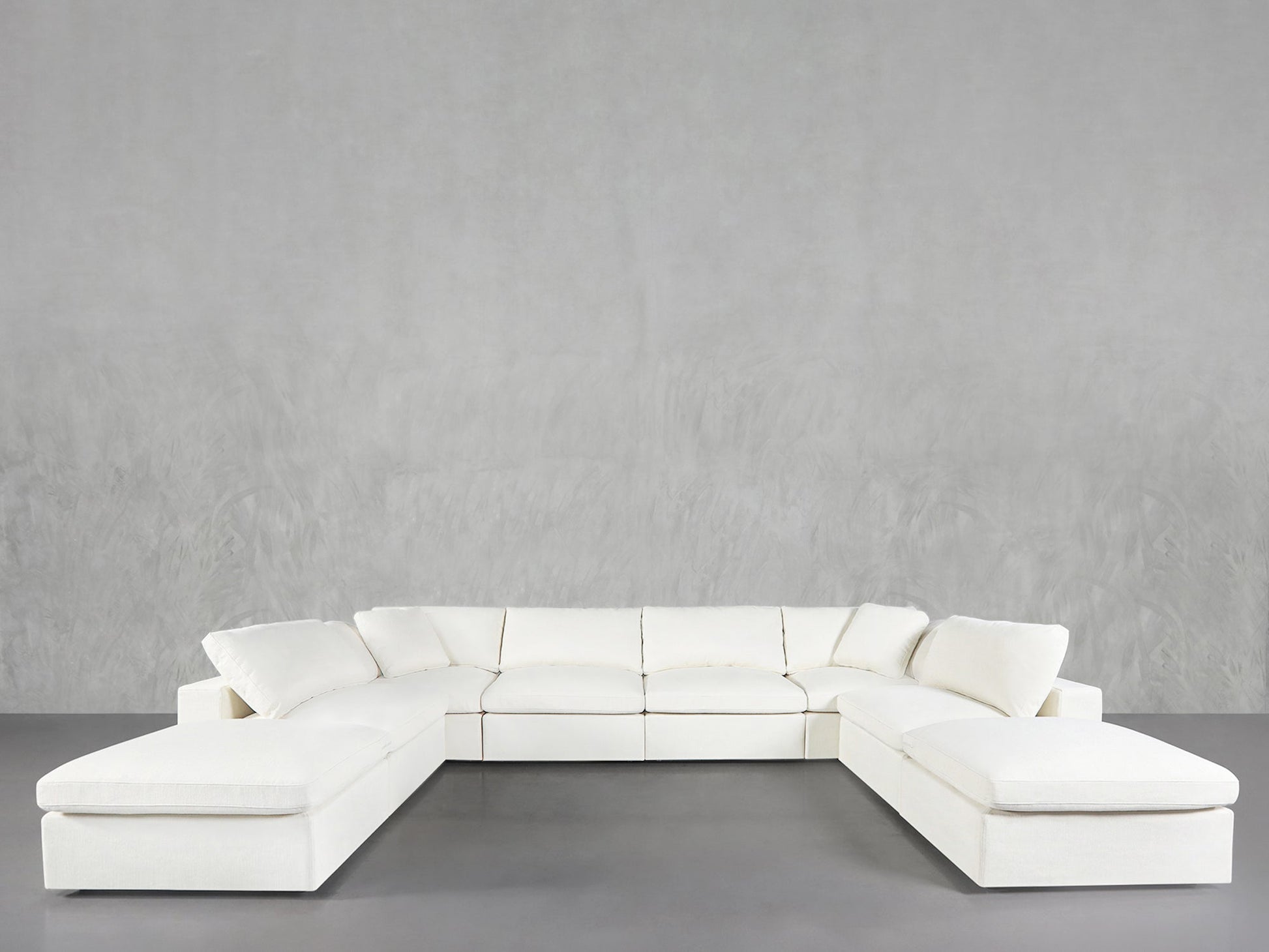 An 8-Seat Modular Double Lounger U-Sectional in modern white is arranged in a U-shape against plain light gray walls and flooring, showcasing clean lines and contemporary style.