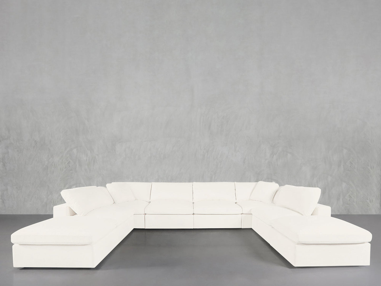 The 8-Seat Modular Double Lounger U-Sectional, a large modern white sofa with clean lines, is arranged in a U-shape against a plain light gray textured wall and gray floor.