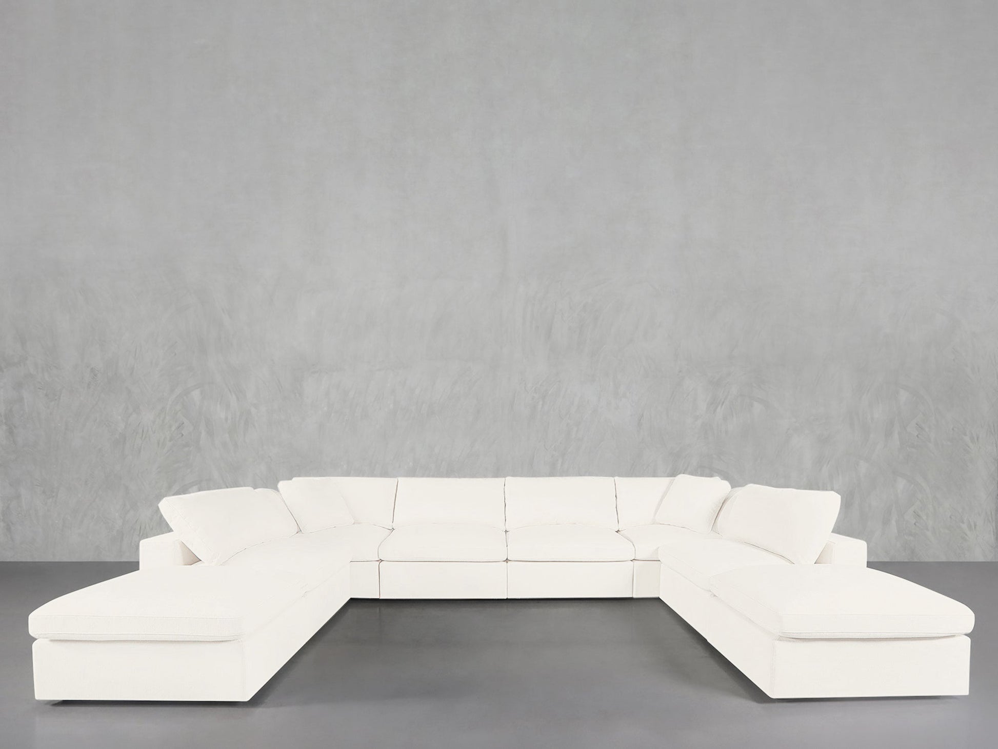 The 8-Seat Modular Double Lounger U-Sectional, a large modern white sofa with clean lines, is arranged in a U-shape against a plain light gray textured wall and gray floor.