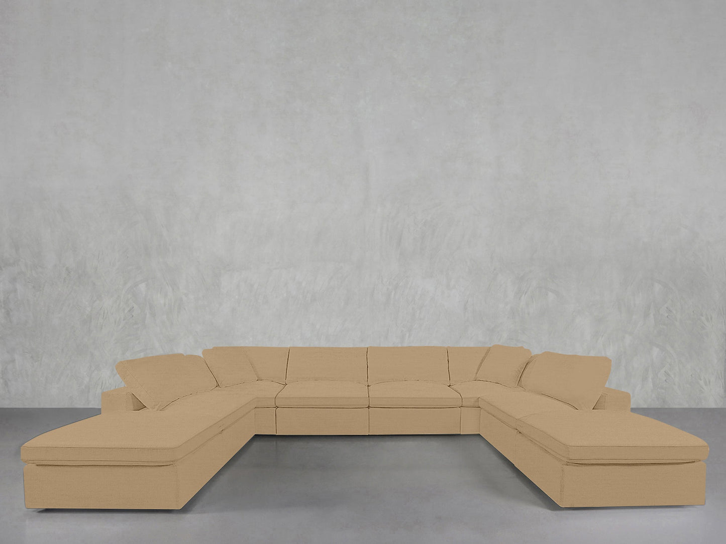An 8-Seat Modular Double Lounger U-Sectional with cushions sits against a plain, light gray textured wall on a smooth gray floor.