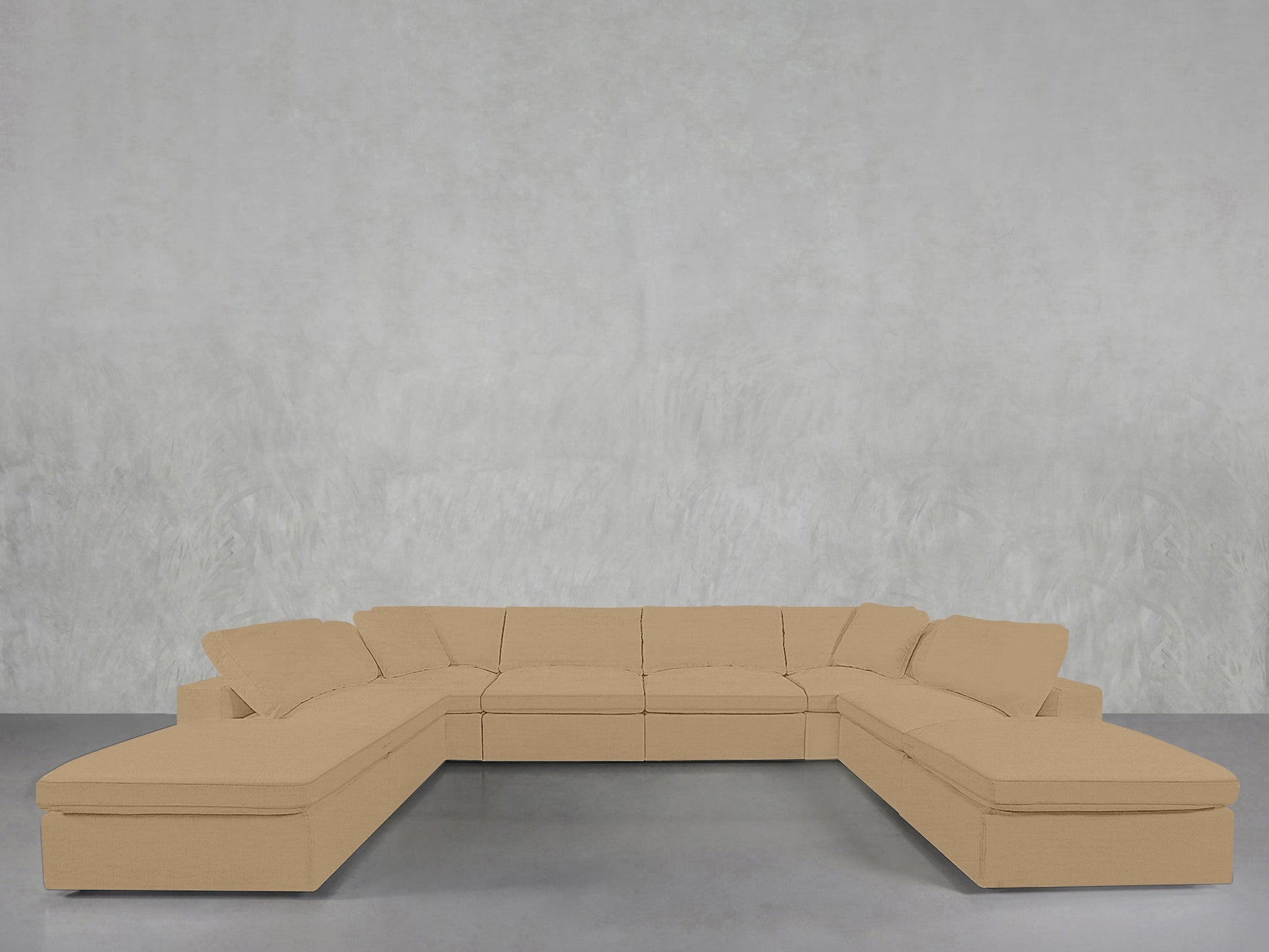 An 8-Seat Modular Double Lounger U-Sectional with cushions sits against a plain, light gray textured wall on a smooth gray floor.
