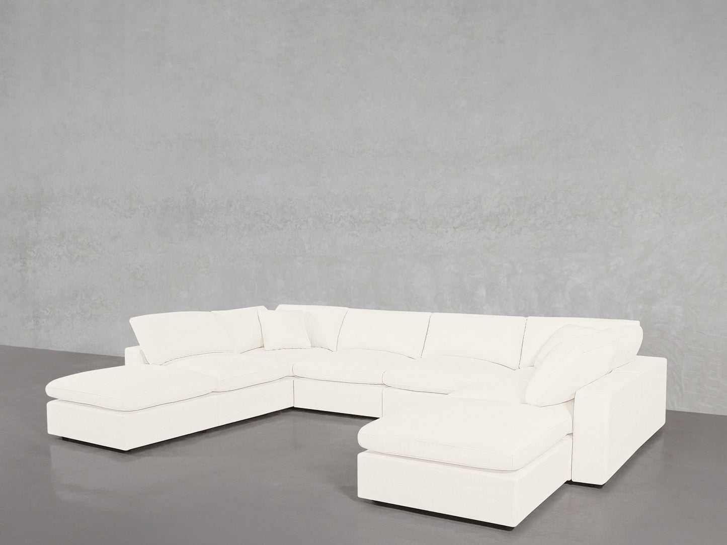 The 8-Seat Modular Double Lounger U-Sectional, featuring plush cushions and a modern white design, is arranged in a spacious U-shape against a plain light gray wall on a smooth gray floor.