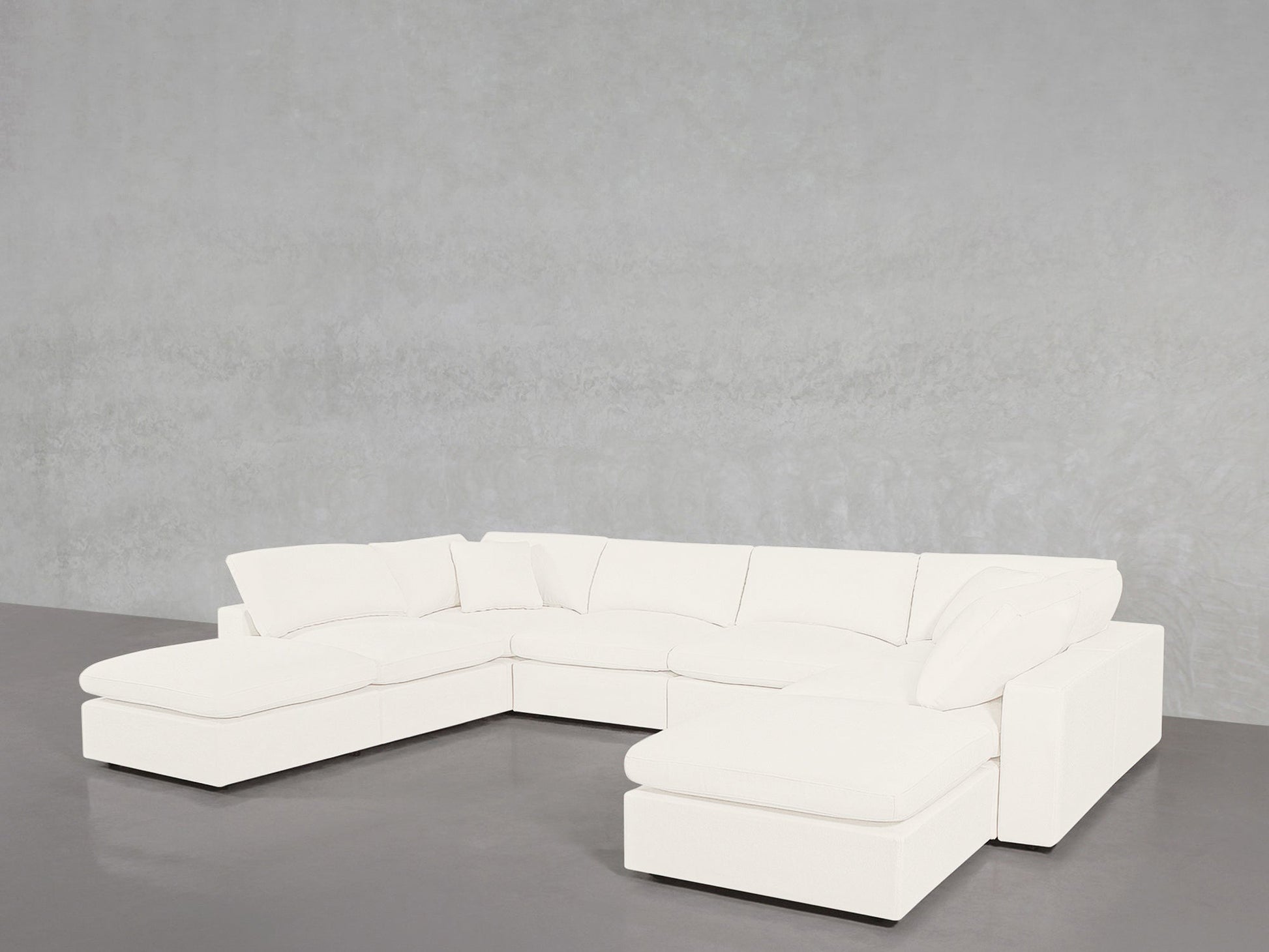 The 8-Seat Modular Double Lounger U-Sectional, featuring plush cushions and a modern white design, is arranged in a spacious U-shape against a plain light gray wall on a smooth gray floor.