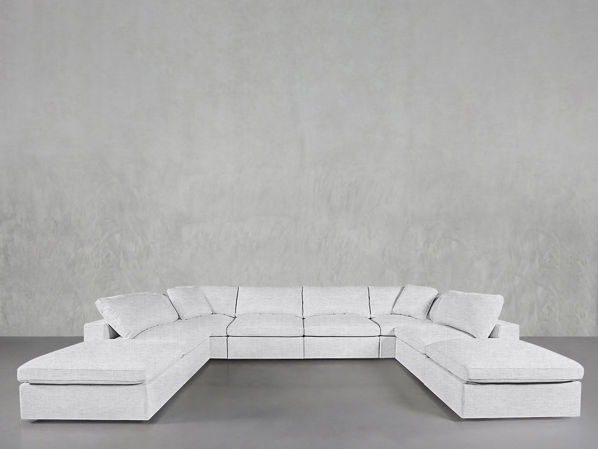 The 8-Seat Modular Double Lounger U-Sectional, in light gray, features wide cushioned seats and backrests, arranged in a minimalist room with matching walls and floors.