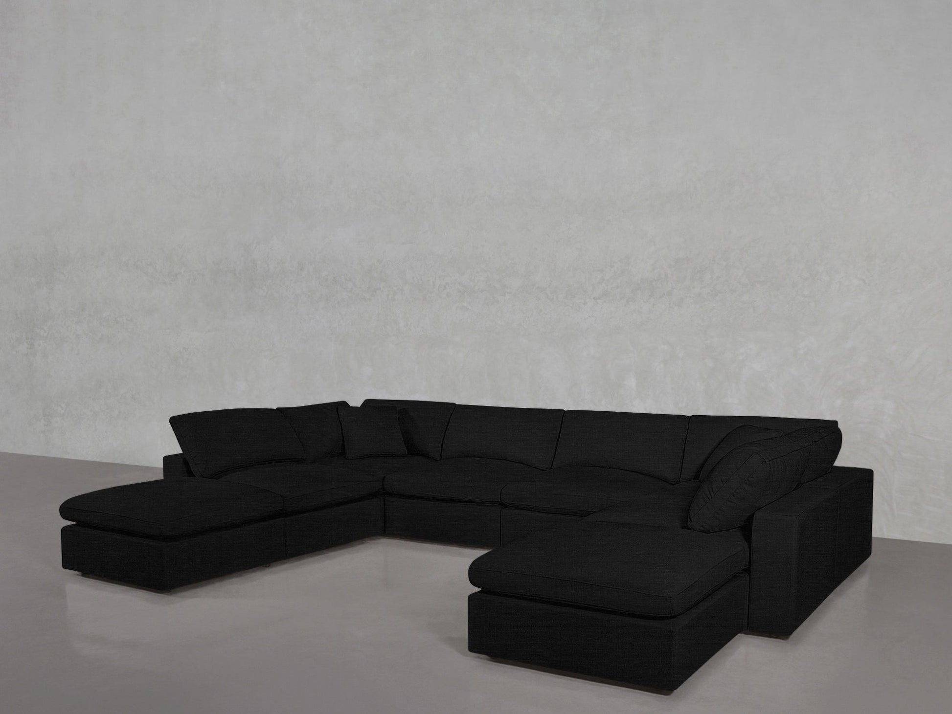An 8-Seat Modular Double Lounger U-Sectional in black, featuring multiple cushions, is arranged against a plain light gray wall on a smooth, glossy floor.