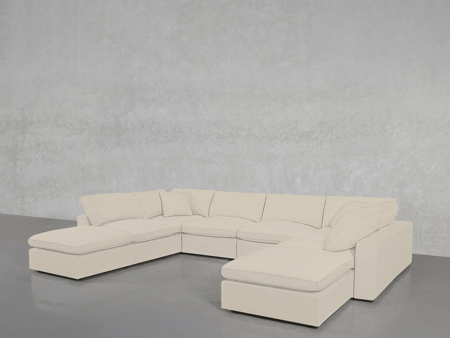 An 8-Seat Modular Double Lounger U-Sectional in beige with plush cushions sits in an empty room featuring a smooth gray floor and a lightly textured gray wall.