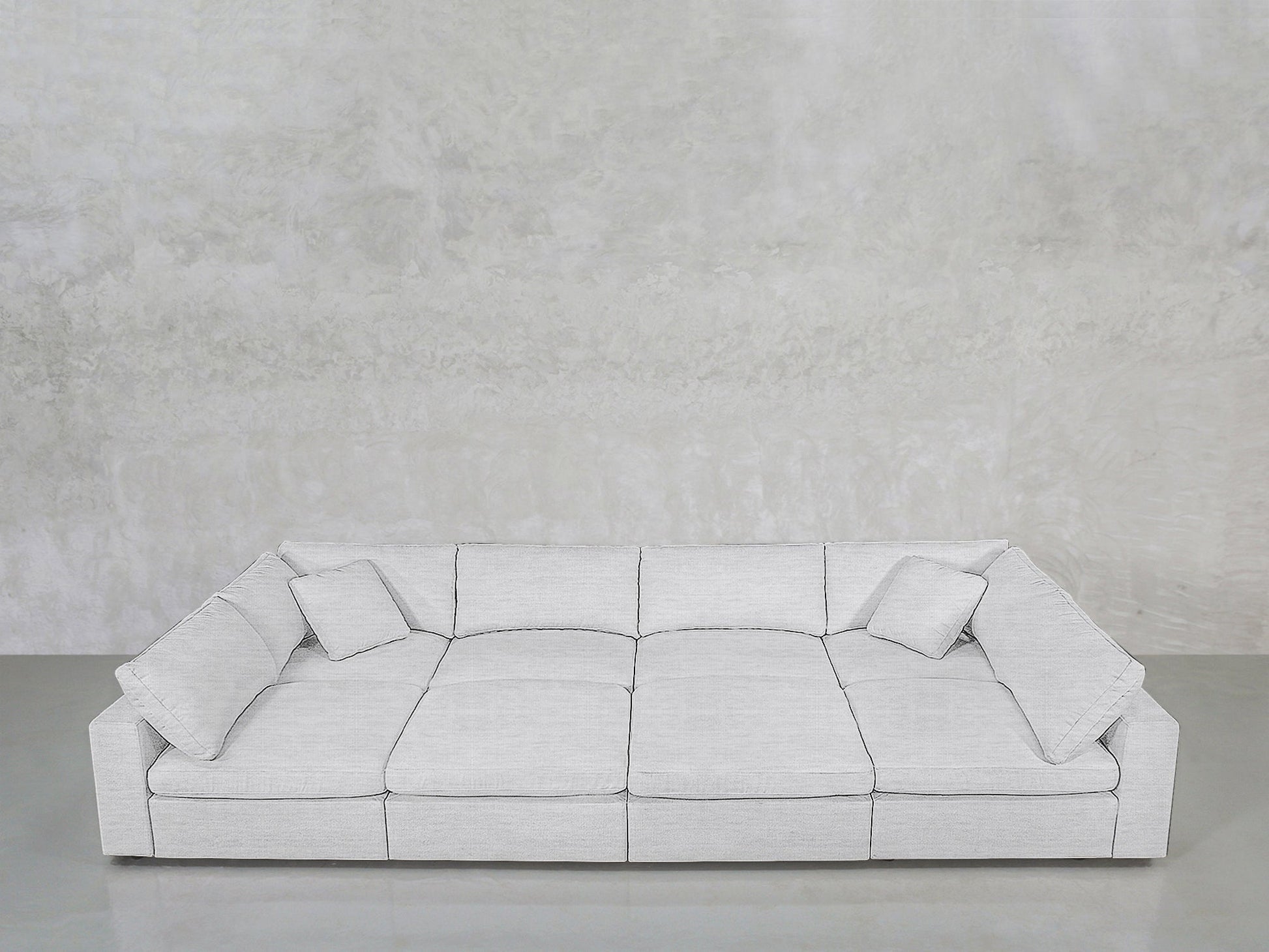 An 8-Seat Modular Pit sectional in light gray with wide seats and four matching cushions sits against a textured light gray wall on a polished concrete floor.