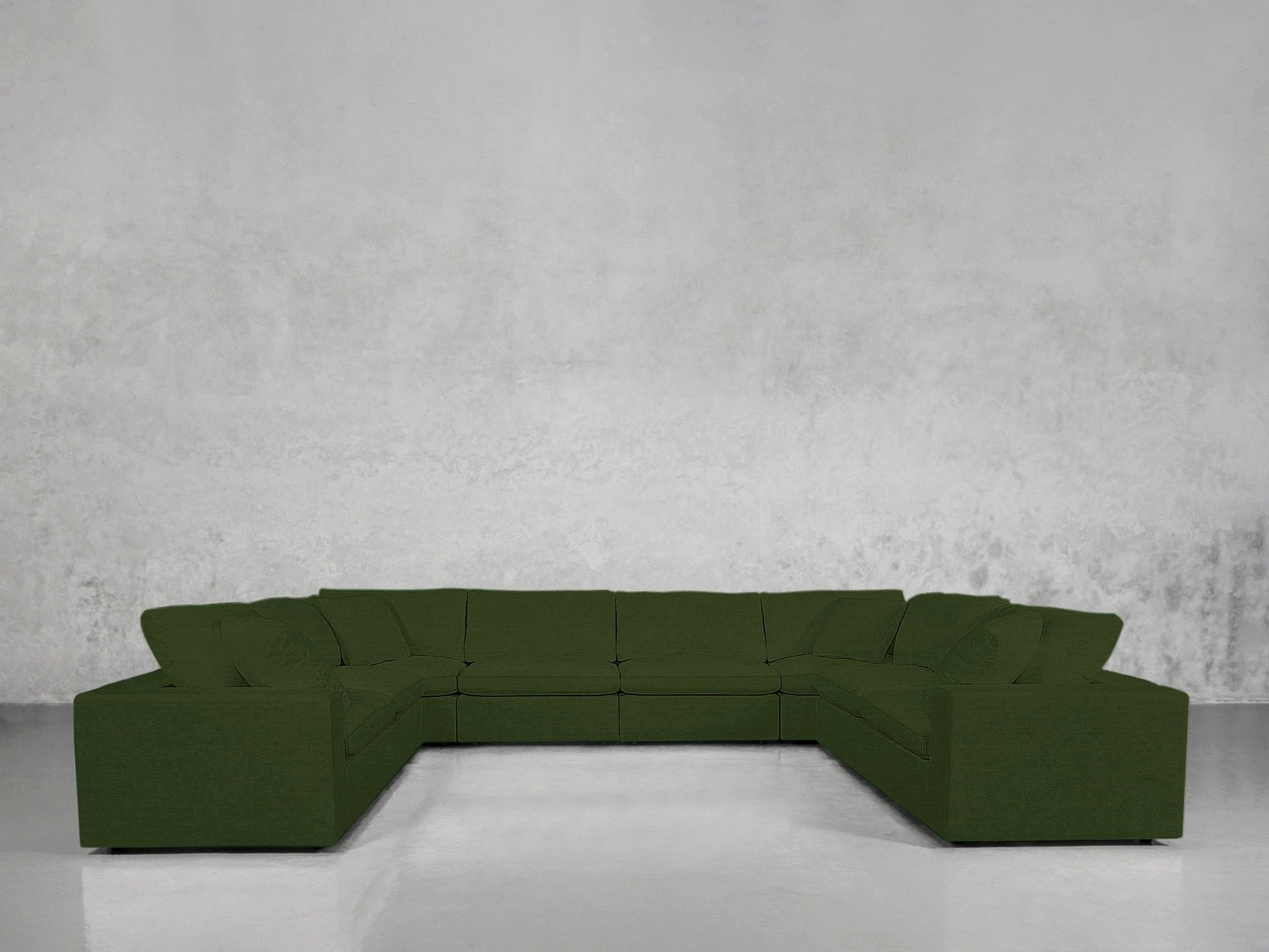 An 8-Seat Modular U-Sectional with a modern design, upholstered in dark green, is arranged in a U-shape against a plain light gray textured wall and a smooth, light-colored floor.