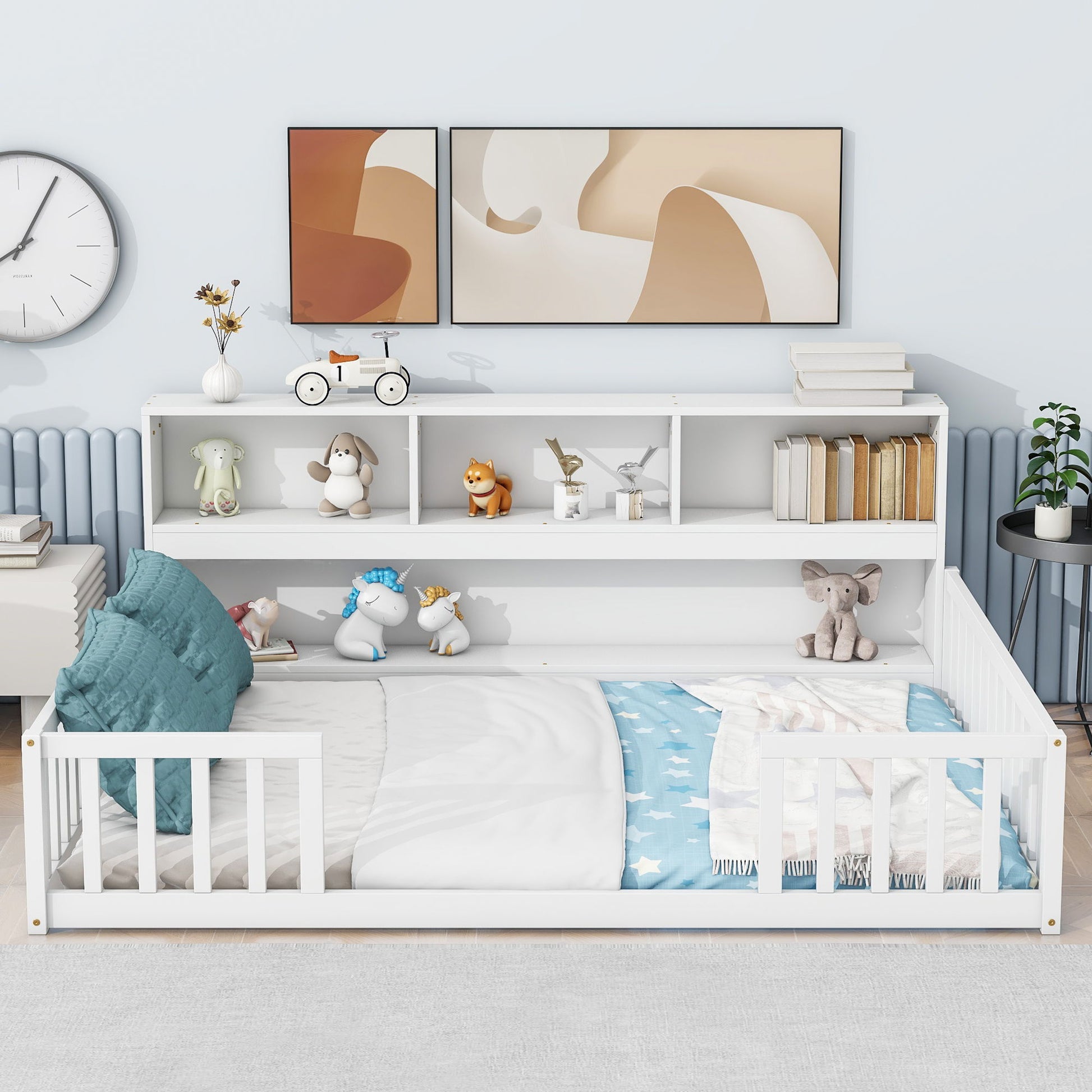 A Floor Bed With Side Bookcase, Shelves, and Guardrails is placed against the wall. Blue pillows and a star-patterned blanket add comfort, while toys, books, abstract art prints, a clock, and a plant decorate the space.