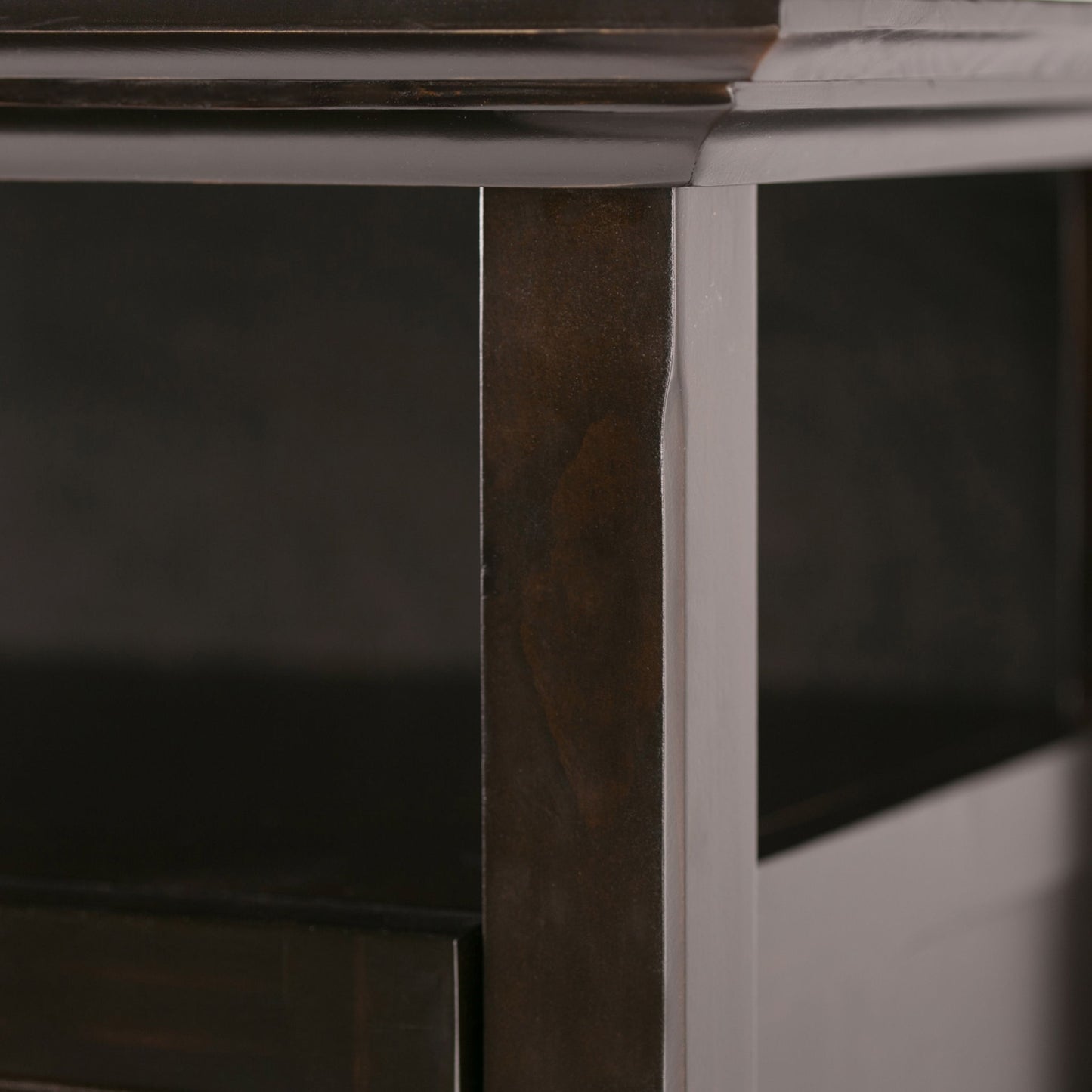Close-up of the Amherst - TV Media Stand, Handcrafted, showing the smooth dark wood surface with visible grain, a slight dent on the vertical edge, and an open shelf beneath.
