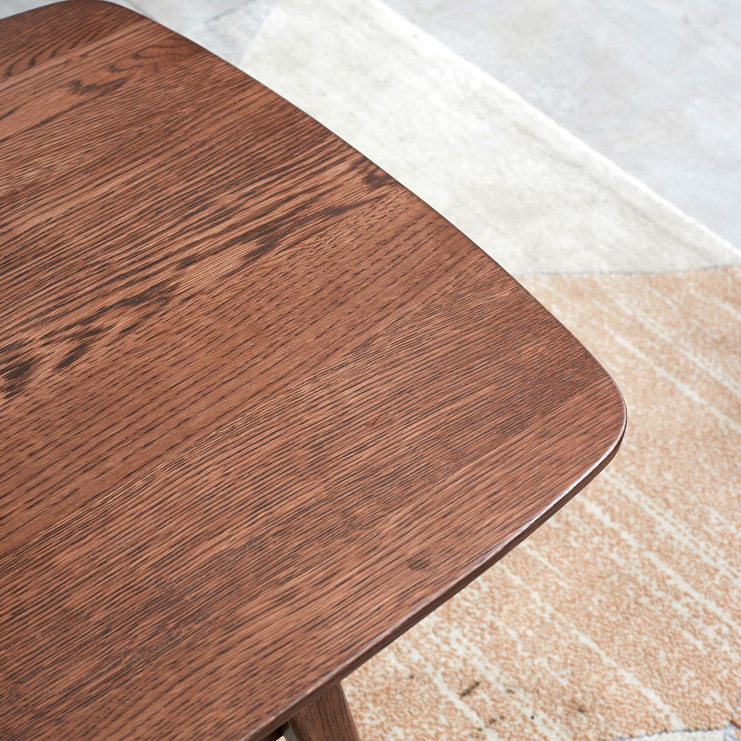 A close-up of the Low Coffee Table With Storage Shelf featuring a smooth, dark brown finish, placed on a beige and gray textured rug atop a light-colored floor.