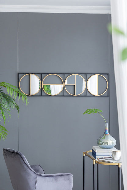 A modern living room corner with a gray wall, an Eclectic Styling Metal Beaded Wall Mirror, a gray velvet chair, a small gold side table with a glass vase, a green plant, and natural light streaming through sheer white curtains.