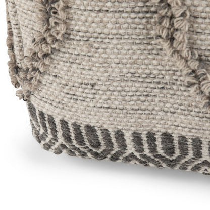 Close-up of the Sweeney Upholstered Square Pouf, showing its woven fabric in neutral tones with a textured, raised pattern and a dark geometric border at the base.
