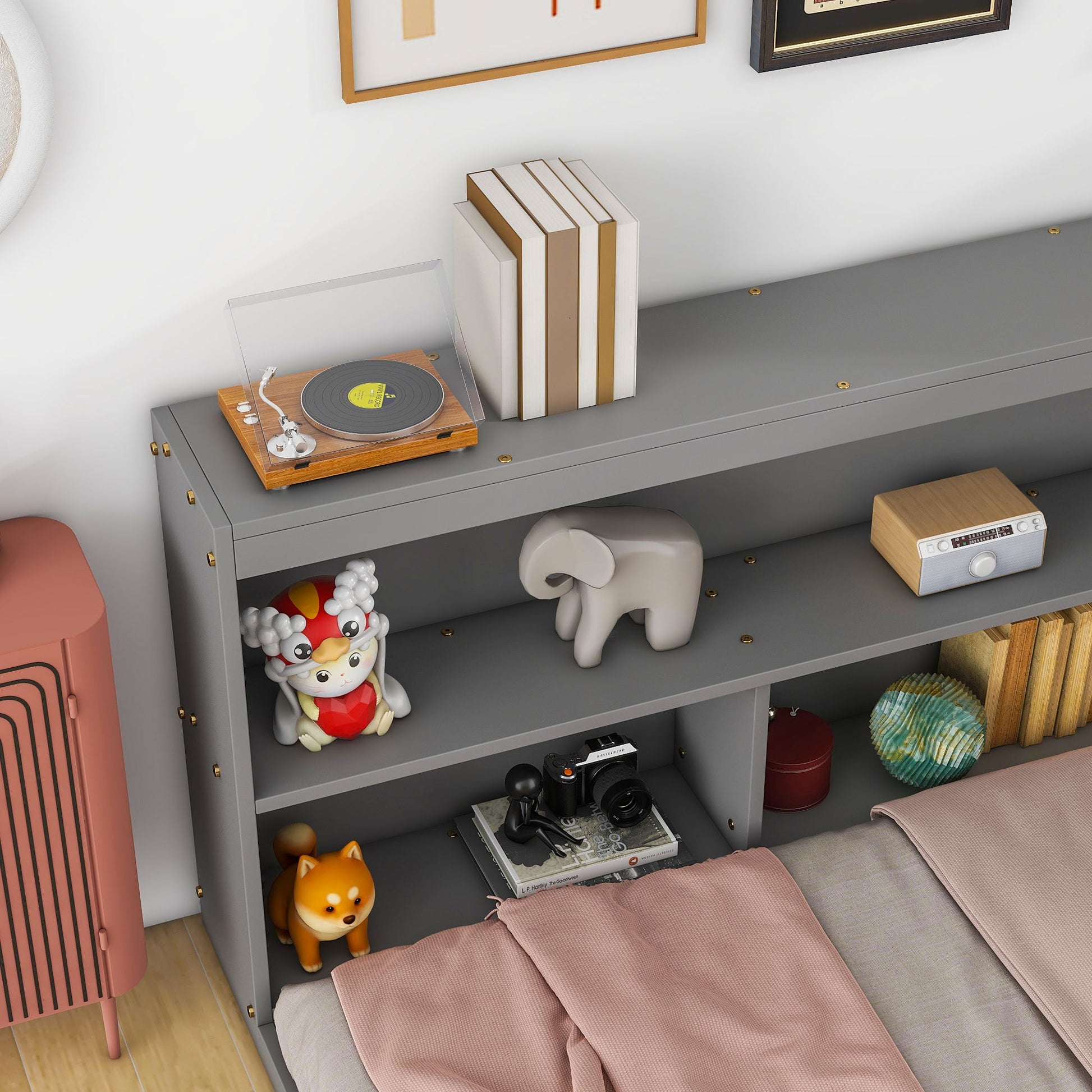 A Floor Bed With L-Shaped Bookcases (Sliding Doors, Without Slats) holds books, a toy turntable, a cartoon animal figure, a gray elephant sculpture, a small radio, camera, globe, and fox figurine. A pink blanket partially covers the bed.