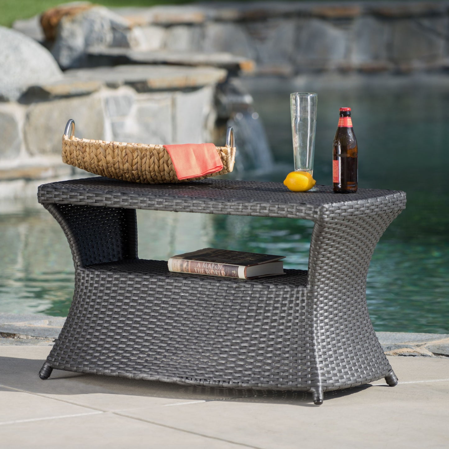 By the pool, the Berkeley - Chaise Lounge Side Table holds a tray with an orange napkin, empty glass, beer bottle, and lemon on top. A book is placed on its lower shelf.