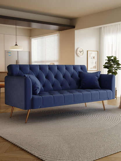 A modern living room features the Convertible Double Folding Living Room Sofa Bed in navy blue with two matching pillows and light wood legs, paired with a round textured rug, potted plant, minimal wall art, and large windows for natural light.