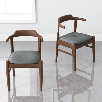 Two Dakota Mid-Century Modern Velvet Dining Chairs (set of 2), featuring curved armrests and gray velvet seats, are arranged on a shiny floor near a white wall and window.
