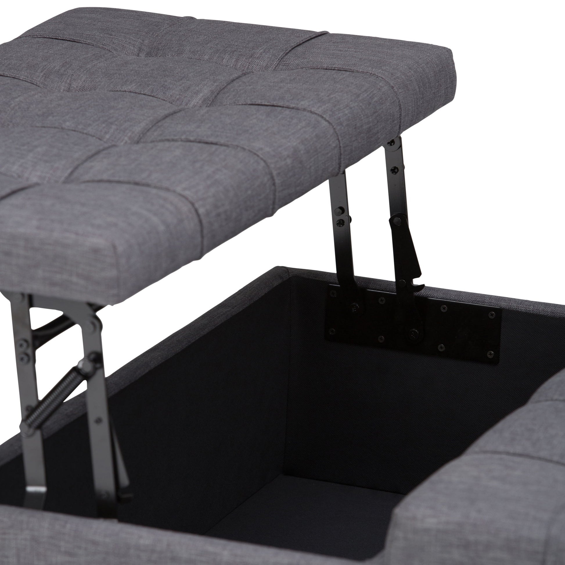 A close-up of the Harrison - Upholstered Coffee Table Storage Ottoman in gray, shown with its cushioned lid open to reveal a spacious inner compartment and sturdy metal lifting hinges.