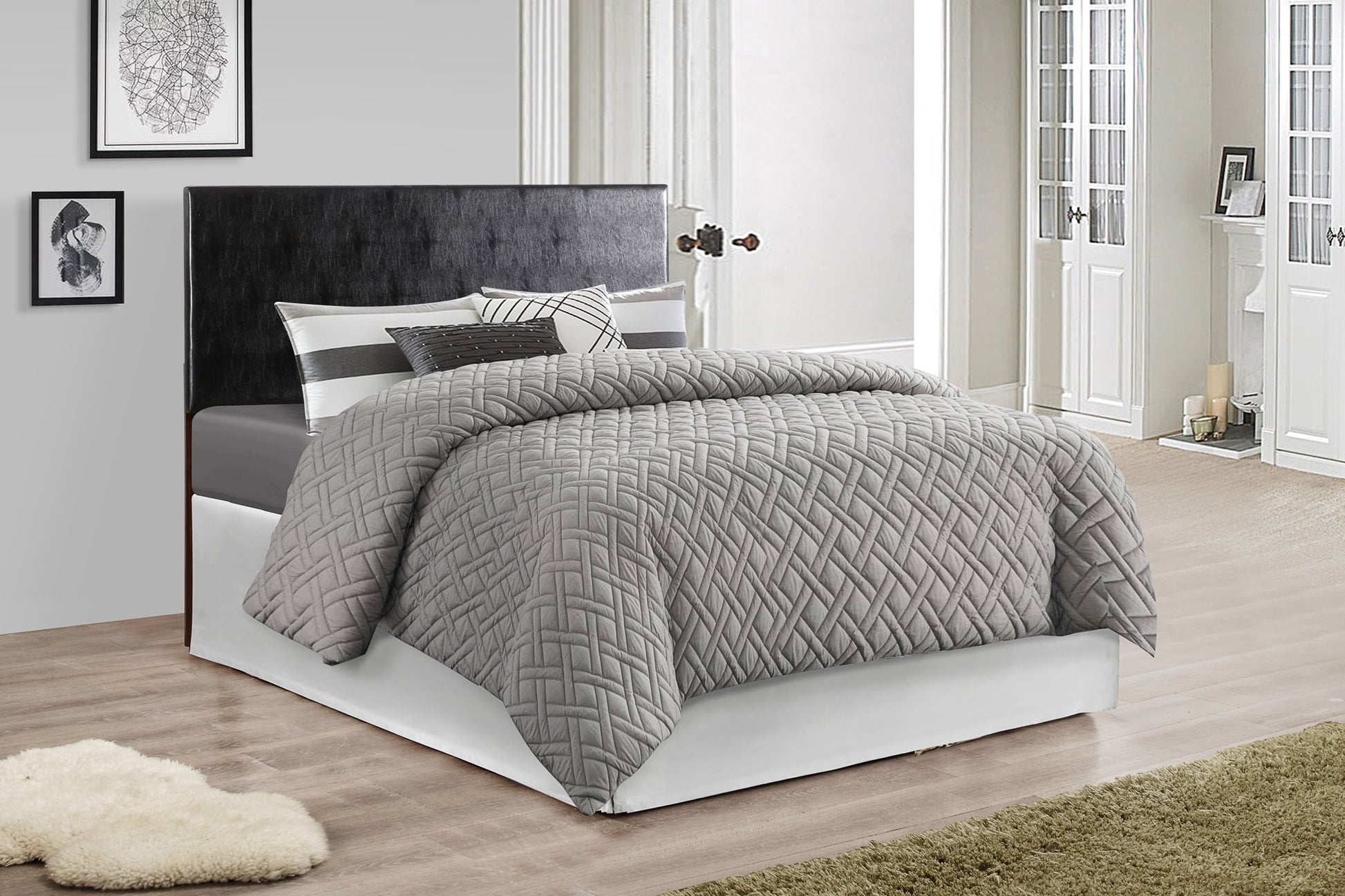 A modern bedroom with the Nova headboard in black, gray quilted bedding, striped pillows, light-colored walls, framed artwork, wooden floors, and a shaggy beige rug.
