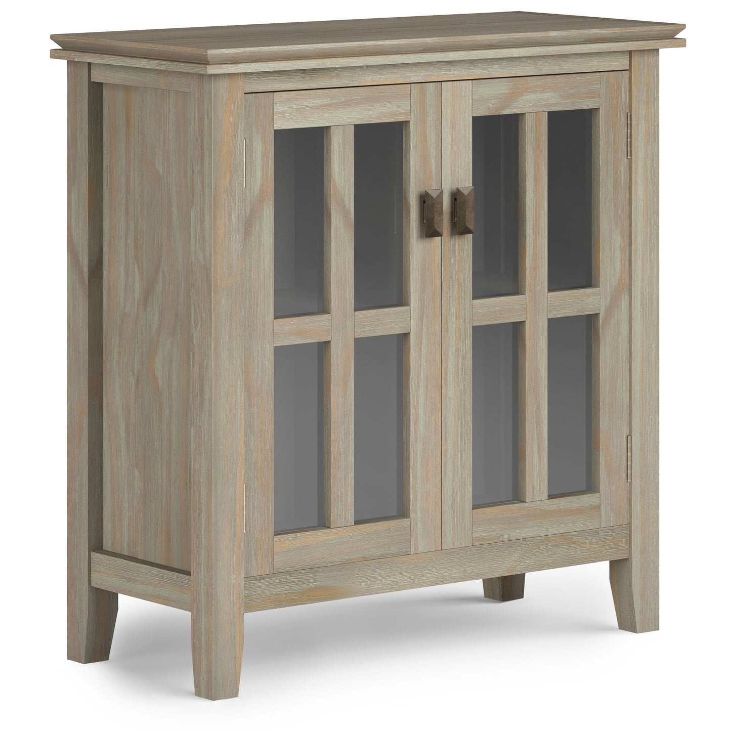 The Artisan - Handcrafted Low Storage Cabinet boasts a light, weathered wood finish, two glass-panel doors with metal handles, and stands on four short legs.