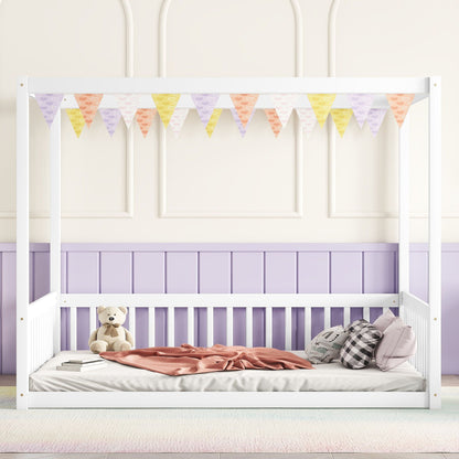 A Canopy Frame Floor Bed With Fence, Guardrails, in white, is adorned with pastel bunting. It features a pink blanket, two plaid pillows, and a teddy bear, set against pastel purple and cream walls.