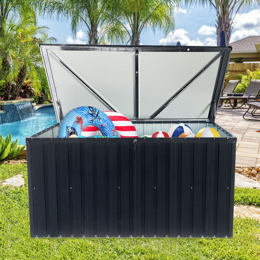 The Metal Storage Box Store Large Out Door Use - Black sits open in a backyard by the pool, surrounded by palm trees and patio furniture, with pool toys like inflatable rings and beach balls visible inside.