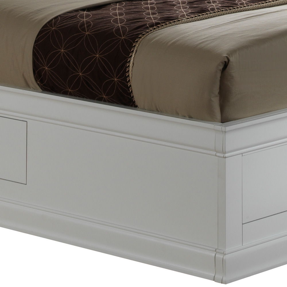 A close-up of the Louis Phillipe - Bookcase Storage Bed’s white wooden frame, shown with a taupe comforter and a brown blanket with a circular geometric pattern draped over the mattress.