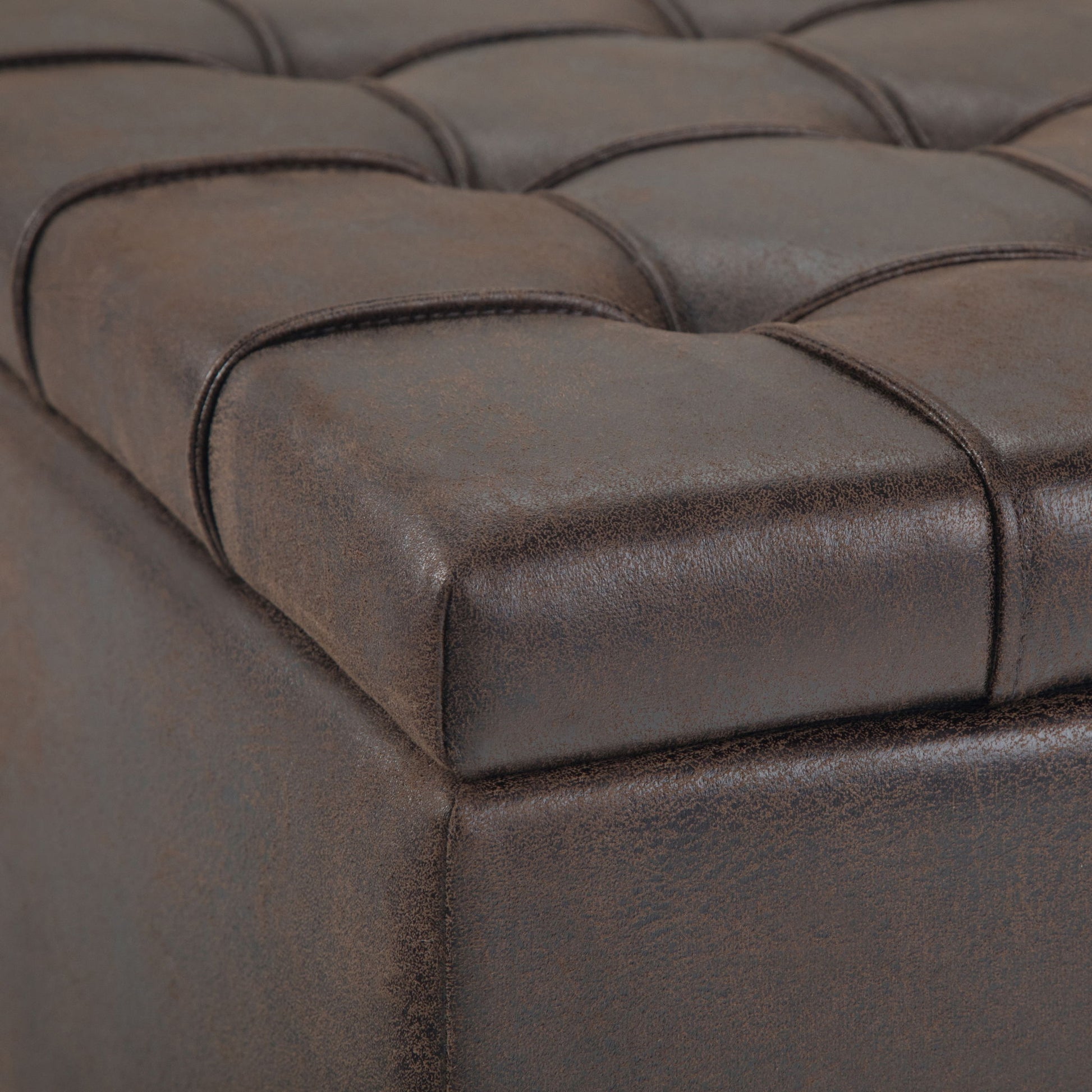 Close-up of the Harrison - Large Coffee Table Storage Ottoman featuring brown, tufted faux leather with visible stitching and detailed cushioned surface and sides.