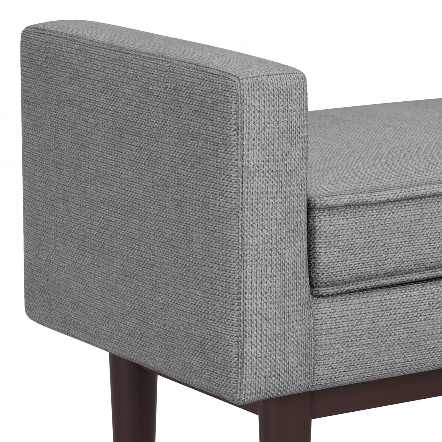 A close-up of the Scott - Upholstered Ottoman Bench highlights its grey fabric, cushioned seat, armrest, and dark wooden legs.