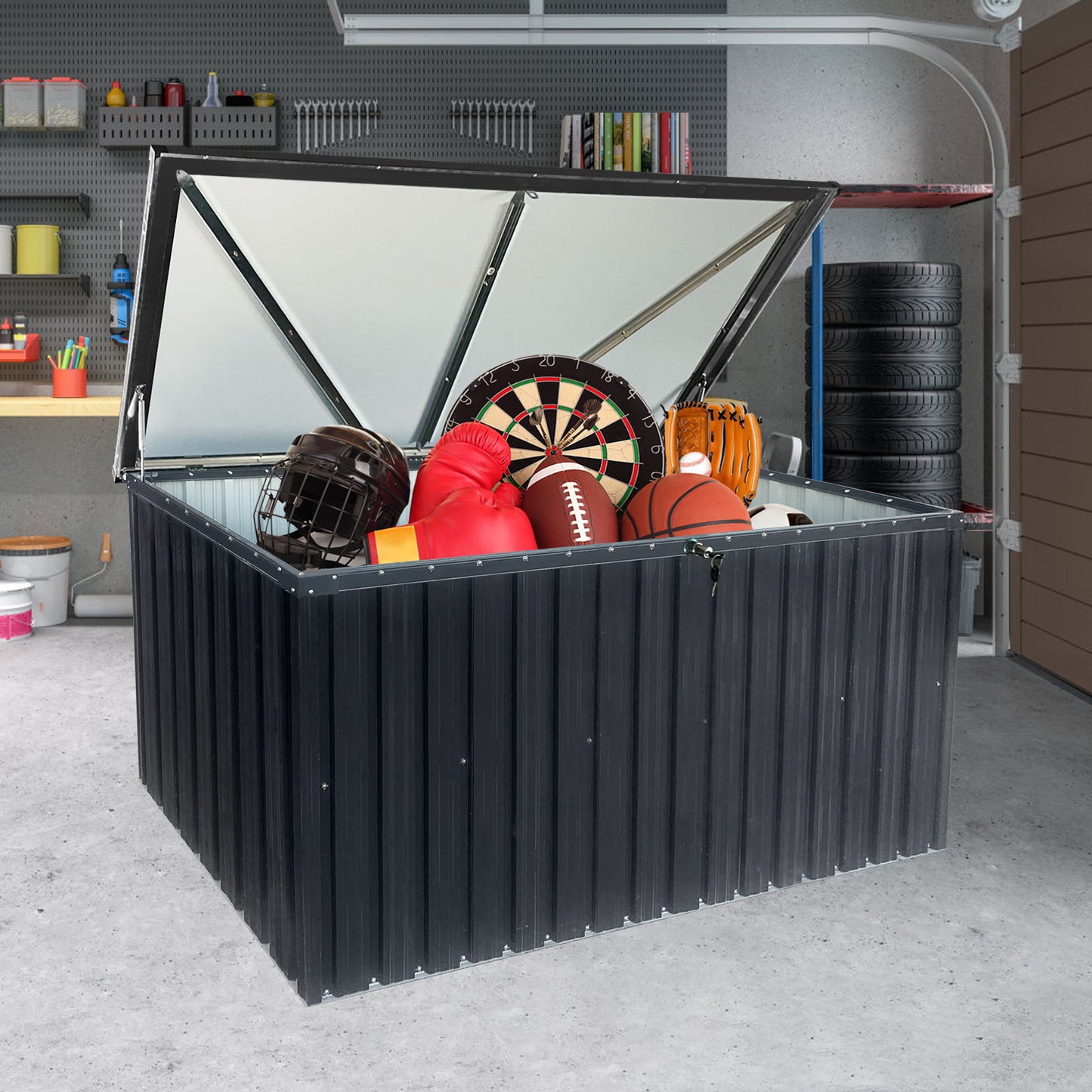 An open Metal Storage Box Store Large Outdoor Use - Black sits in a garage, displaying sports gear like a basketball, football, baseball helmet, boxing gloves, and a dartboard. Shelves and stacked tires are in the background.