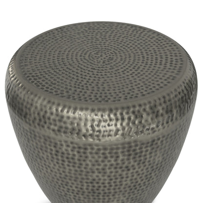 A close-up of the Preston - Handcrafted Metal Side Table highlights its round shape, hammered texture, and dark gray metallic finish, focusing on the top surface and upper sides.