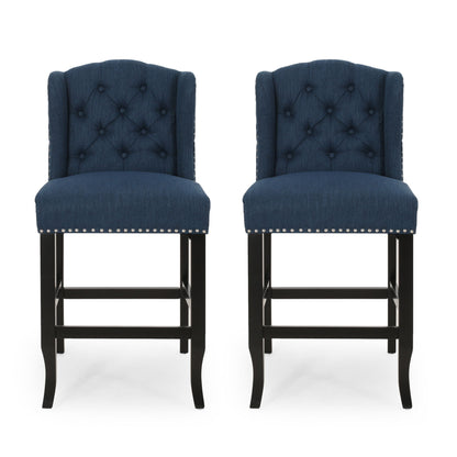 The Vienna Fabric Tufted Counter Stool With Nailhead Accents (Set of 2) features navy blue upholstery, button-tufted backs, silver nailhead trim, and dark wooden legs, shown side by side against a white background.