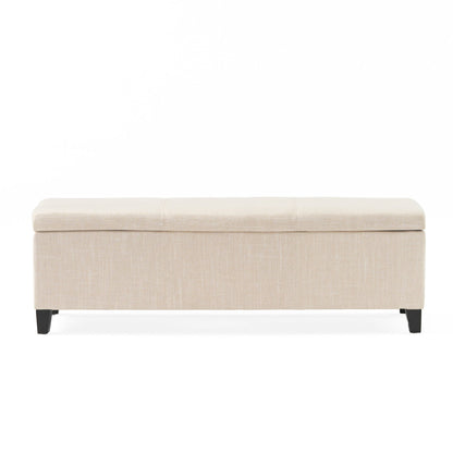 The Glouster - Contemporary Storage Ottoman is a rectangular beige upholstered bench with a cushioned top and four short dark wooden legs, shown against a plain white background.