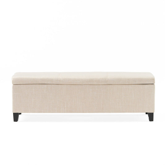 The Glouster - Contemporary Storage Ottoman is a rectangular beige upholstered bench with a cushioned top and four short dark wooden legs, shown against a plain white background.