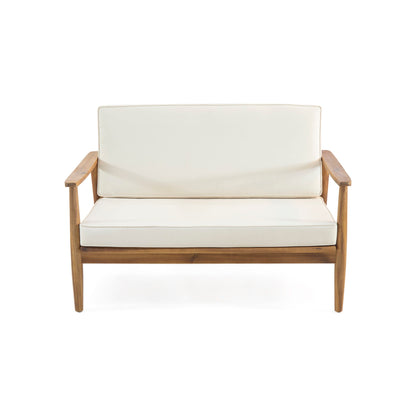 The Outdoor Acacia Wood Loveseat Set With Coffee Table features a wooden frame, straight armrests, and cream seat and back cushions, displayed against a white background.