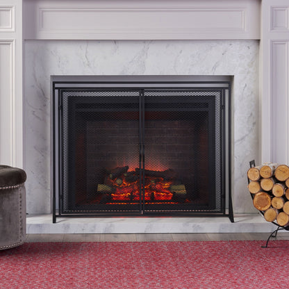 The Samantha - Iron Fireplace Screen 2 Door Design stands in front of a modern fireplace with glowing logs, marble surround, firewood stacked on the right, and a red textured rug covering the floor in front.