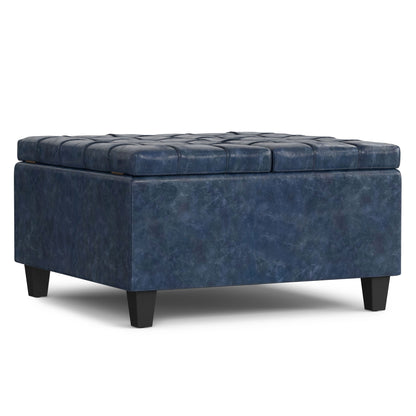 The Harrison Upholstered Coffee Table Storage Ottoman features a square blue tufted cushioned lid, textured fabric upholstery, short black legs, and a modern design.