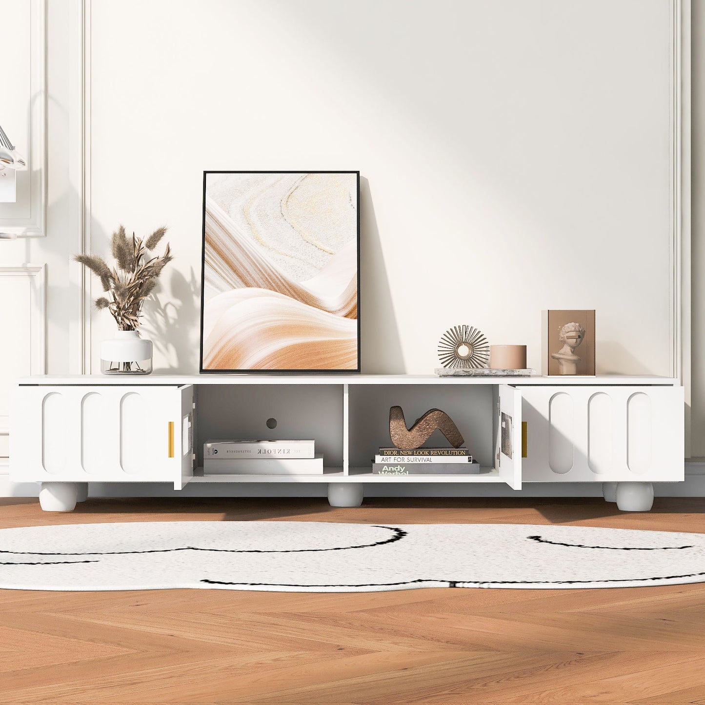 A Modern TV Stand for TVs up to 80" with glass door, 2 drawers, and cabinets displays abstract art, decor, books, and a vase on a light wood floor with a white and black rug in a bright, minimalist living space.