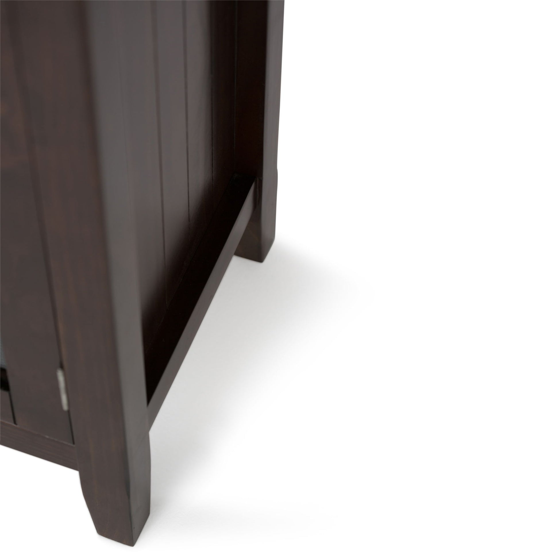 Close-up of the lower corner of the Acadian Low Storage Cabinet in Brunette Brown, highlighting its legs and side panel against a white background.