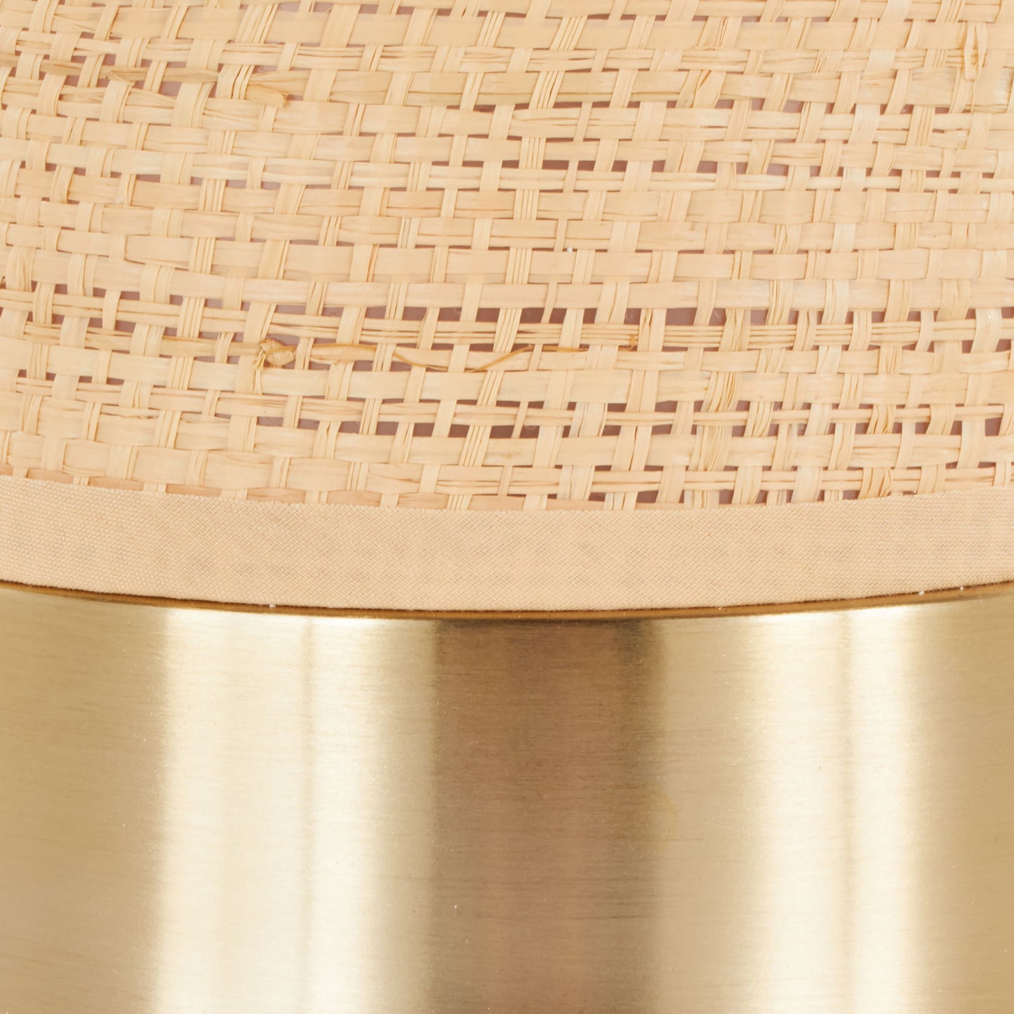 A close-up of the Cylinder - Rattan Contemporary Rattan Table Lamp shows a woven rattan texture on the top half and a smooth, shiny brass band on the bottom.