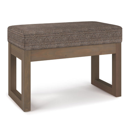 The Milltown - Upholstered Ottoman Bench features a brown cushion and wooden legs, showcased from an angle against a white background.