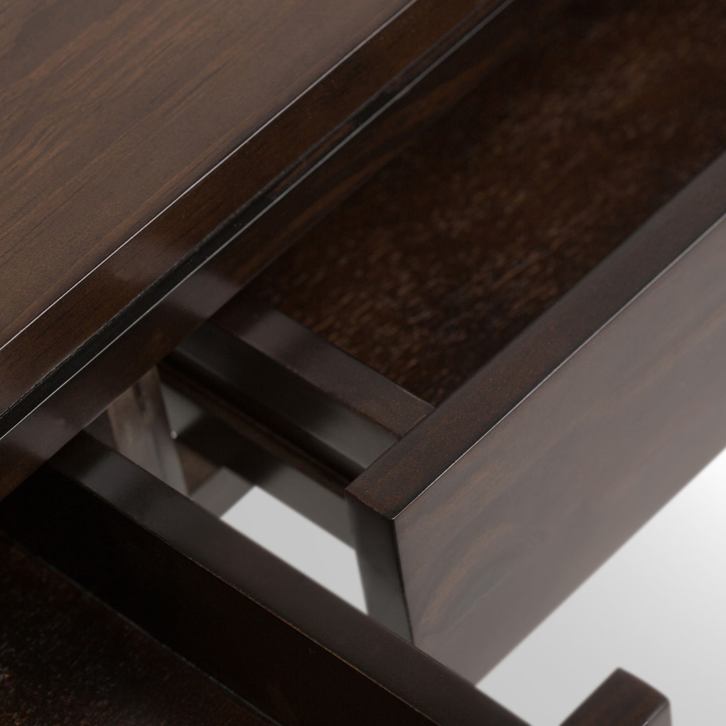 Close-up view of an open drawer in the Cosmopolitan Multipurpose Table, revealing its smooth interior and a glimpse of the table’s glossy dark wood exterior.