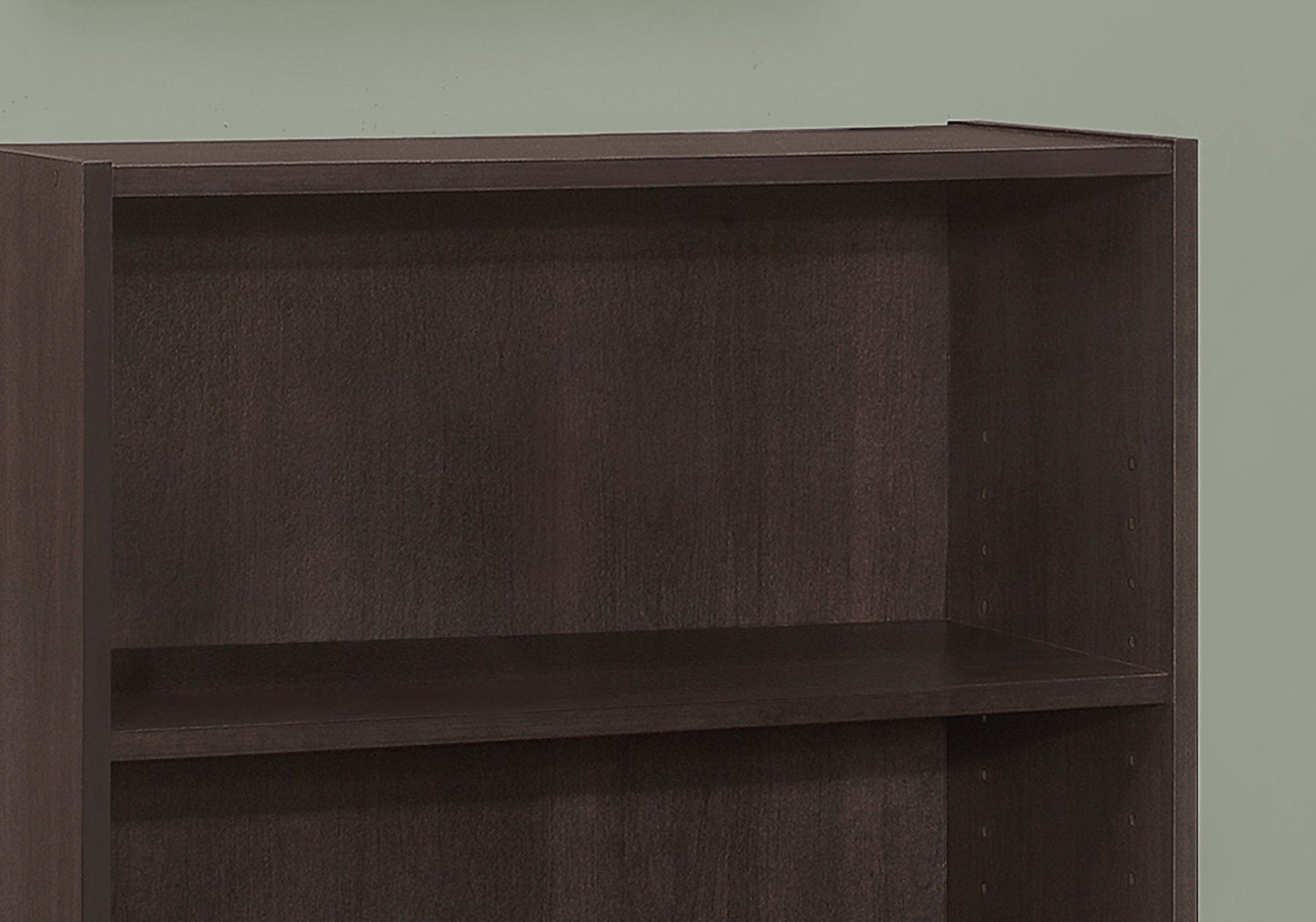 A close-up of an empty dark brown 4-tier transitional bookshelf, ideal for office use, placed against a plain light green wall.
