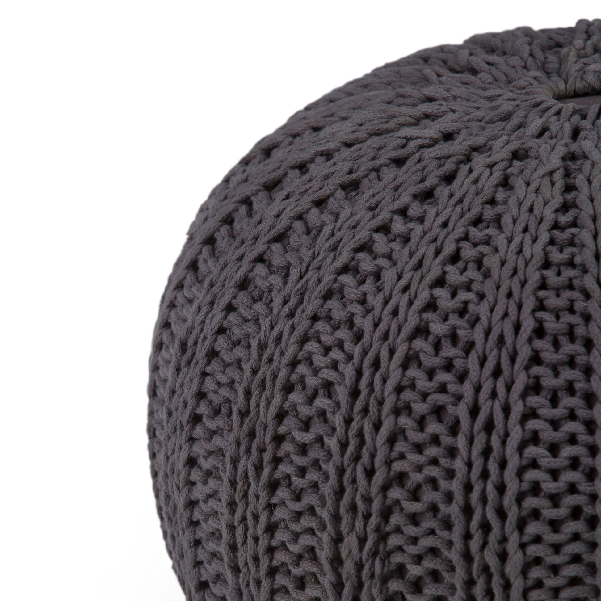 Close-up of the Shelby - Handcrafted Hand Knit Round Pouf in dark gray, featuring thick yarn and a textured ribbed pattern, partially visible against a white background.
