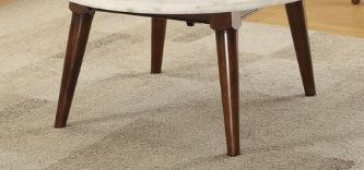 A close-up of the lower half of the Gasha Coffee Table in white marble with angled walnut legs, set on a light-colored carpet.